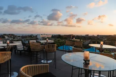 a rooftop patio with tables and chairs at sunset at Imani Suites in Seminyak