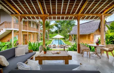 a patio with a couch and a table and a pool at Alea Estate in Kerobokan