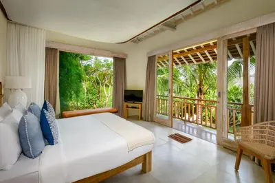a bedroom with a white bed and large windows at Alea Estate in Kerobokan