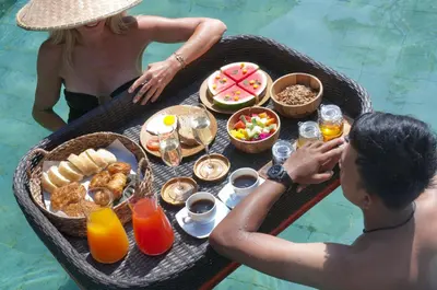a man and woman sitting at a table with a tray of food at 2BR Villa Senin - Minggu Villas Seminyak in Seminyak