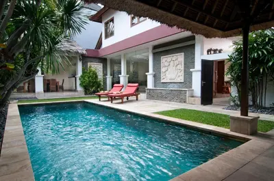 a swimming pool in front of a villa at 4BR Villa Selasa - Minggu Villas Seminyak in Seminyak