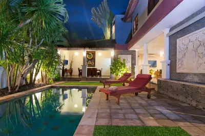 a house with a pool and a red chair next to it at 4BR Villa Selasa - Minggu Villas Seminyak in Seminyak