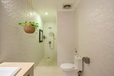 a white bathroom with a toilet and a shower at Villa Sarong 2 Chic 2BR Boho Villa Prime Central Location in Seminyak