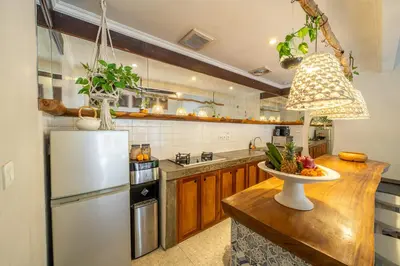a kitchen with a refrigerator and a table with a bowl of fruit at Villa Sarong 2 Chic 2BR Boho Villa Prime Central Location in Seminyak