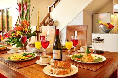 a wooden table topped with plates of food and wine glasses at Alysha Villa Seminyak Beachside By Bali Asia Villa in Seminyak