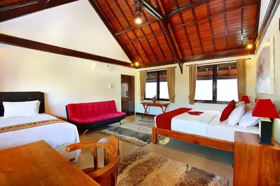 a bedroom with two beds and a red couch at Alysha Villa Seminyak Beachside By Bali Asia Villa in Seminyak