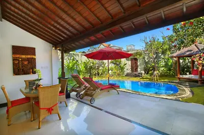 a patio with chairs and an umbrella and a pool at Alysha Villa Seminyak Beachside By Bali Asia Villa in Seminyak