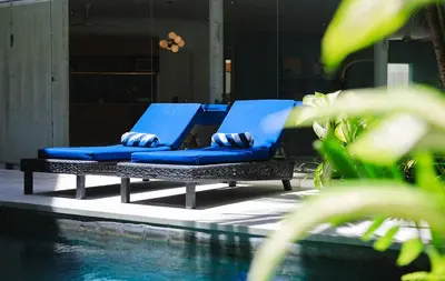 a pair of blue lounge chairs next to a pool at Villa Ungava in Seminyak