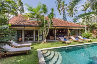 a villa with a swimming pool in front of a house at Villa Kundalini in Seminyak
