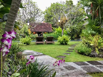 a garden with a table and chairs and flowers at Bali Villa Aja in Seminyak