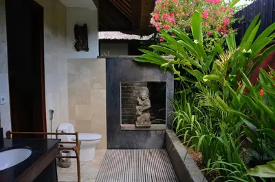 a bathroom with a toilet and a statue in it at Bali Villa Aja in Seminyak