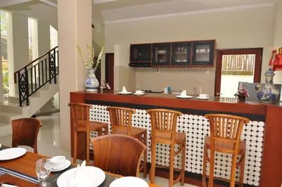 a kitchen with a bar with wooden chairs at Kandava Villa in Jimbaran