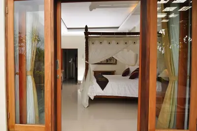 a bedroom with a bed and a glass door at Kandava Villa in Jimbaran