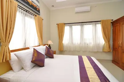 a bedroom with a large white bed with windows at Kandava Villa in Jimbaran