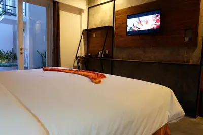 a bedroom with a bed with a television on the wall at Semimpi in Canggu