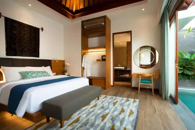 a bedroom with a bed and a bathroom with a mirror at S18 Bali Villas in Legian
