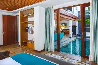 a bedroom with a swimming pool next to a house at S18 Bali Villas in Legian