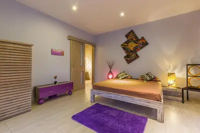 a bedroom with a bed and a purple rug at Villa Purple in Legian