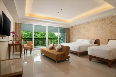 a bedroom with two beds and a couch and a chair at Sulis Beach Hotel & Spa in Kuta