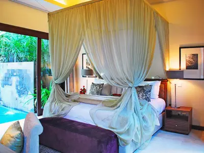 a bedroom with a large bed with a canopy at Kanishka Villas in Seminyak