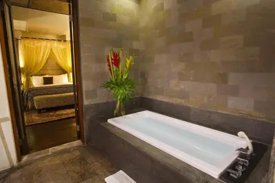 a bath tub with a vase of flowers in a bathroom at Kanishka Villas in Seminyak