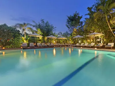 a swimming pool with chairs and umbrellas at a resort at Bali Agung Village in Seminyak