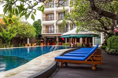 a pool with blue lounge chairs next to a building at Best Western Resort Kuta in Kuta