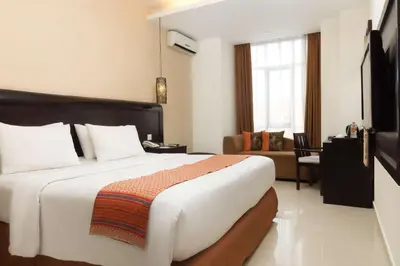 a bedroom with a large bed and a living room at Best Western Resort Kuta in Kuta