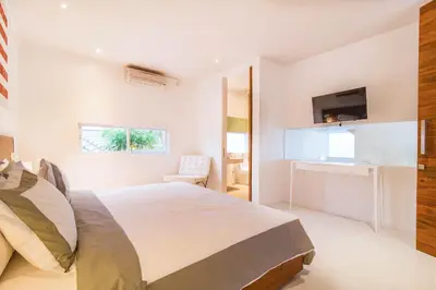 a white bedroom with a bed and a desk at Villa Kamag Seminyak in Seminyak