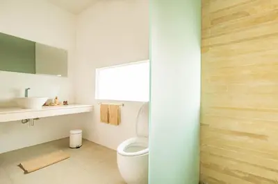 a white bathroom with a toilet and a window at Villa Kamag Seminyak in Seminyak