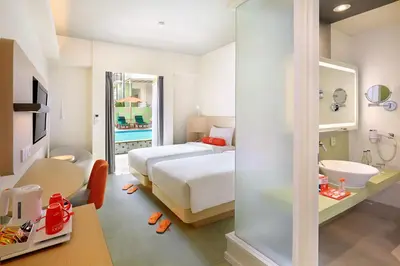 a bedroom with a bed and a bathroom with a sink at HARRIS Hotel Kuta Tuban Bali in Kuta