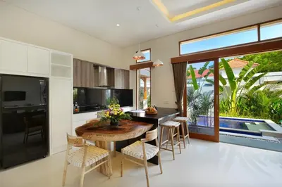 a kitchen with a wooden table and chairs at Holl Villa by Wildflower Group in Legian