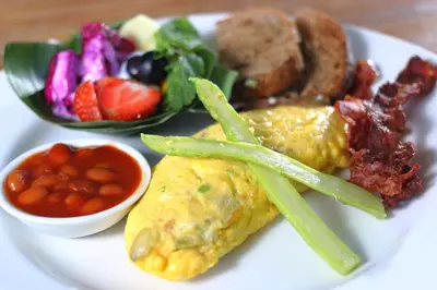 a plate of breakfast food with a omelet and vegetables at Villa Jerami & Spa in Seminyak