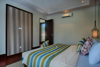 a bedroom with a bed with a striped blanket at Natya Villa Jimbaran in Jimbaran