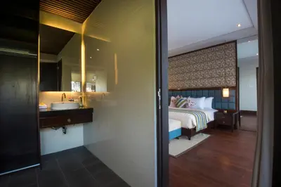 a bedroom with a bed and a bathroom with a sink at Natya Villa Jimbaran in Jimbaran
