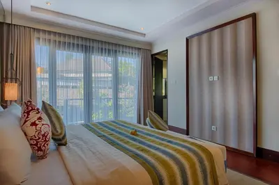 a bedroom with a large bed with a large window at Natya Villa Jimbaran in Jimbaran