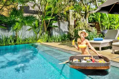 a woman in a bikini sitting in a basket of food next to a pool at Mayaloka Villas Seminyak in Seminyak