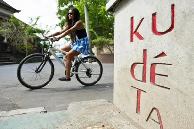 a woman riding a bike down a street at Akara Villa in Seminyak