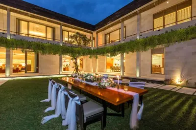 a long table with white chairs in a yard at Villa Seriska Jimbaran - Spacious 5BR Private Pool Villa with Private Cook, Spa & Tour in Jimbaran