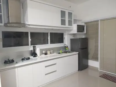 a kitchen with white cabinets and a black refrigerator at Wika Bali Beach House in Jimbaran