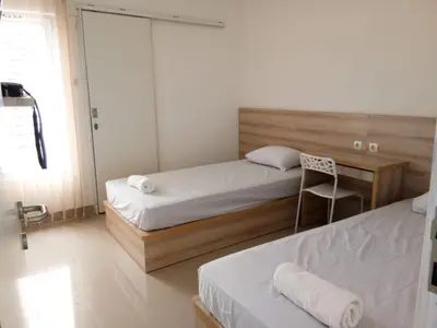 a bedroom with two beds and a chair in it at Wika Bali Beach House in Jimbaran
