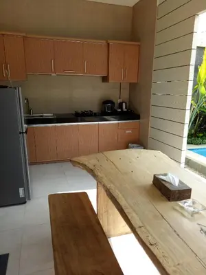 a kitchen with a wooden table and a refrigerator at The Surya Kuta Villa in Kuta