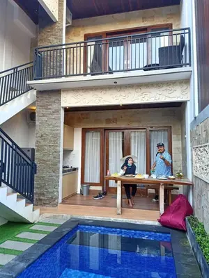 two people sitting at a table in front of a house at The Surya Kuta Villa in Kuta