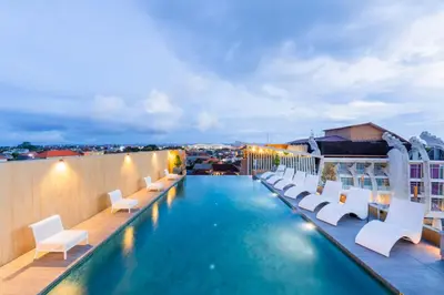 a pool on the roof of a building with white chairs at Stark Boutique Hotel and Spa in Kuta