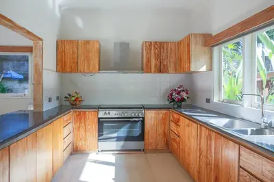 a kitchen with wooden cabinets and a stove top oven at Villa La Luvier in Canggu