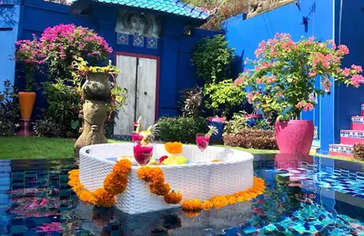 a garden with a table in the water with flowers at Villa Majorelle Bali in Seminyak