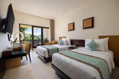 a hotel room with two beds and a television at Adhi Jaya Hotel in Kuta