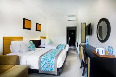 a hotel room with two beds and a mirror at Adhi Jaya Hotel in Kuta