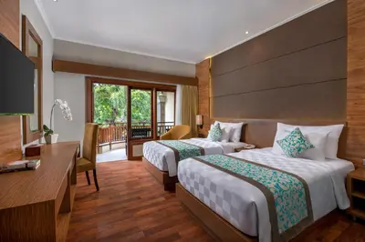 a hotel room with two beds and a desk at Adhi Jaya Hotel in Kuta