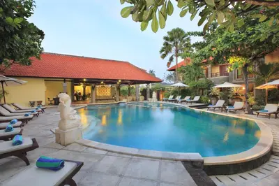 a swimming pool at a resort with lounge chairs at Adhi Jaya Hotel in Kuta